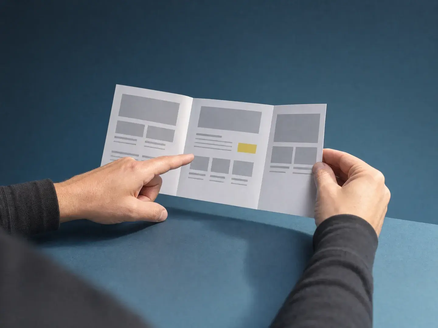 Handen vergelijken drie papieren pagina-indelingen op een blauwe tafel